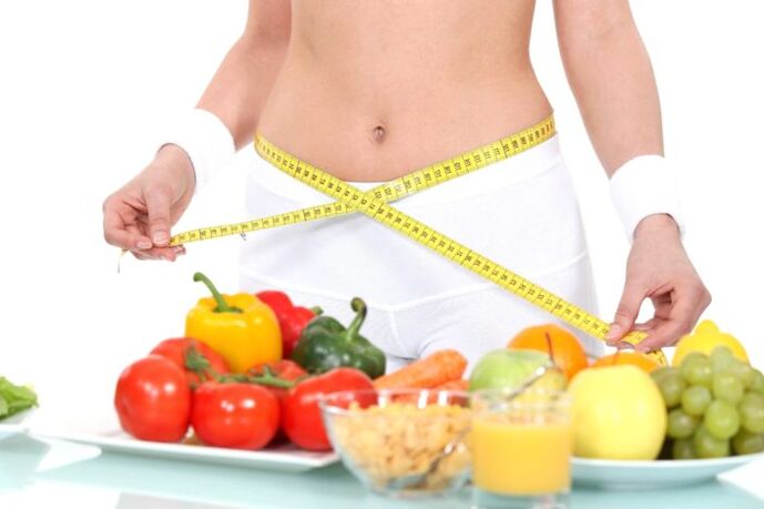 Fata măsoară talia pe fundalul alimentelor
